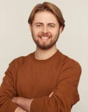 Um retrato profissional de um jovem sorridente com os braços cruzados, simbolizando confiança, confiabilidade e uma personalidade acolhedora.